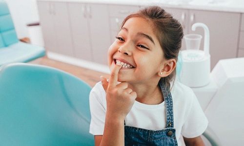 little girl points to teeth after fluoride treatment from Braintree dentist 