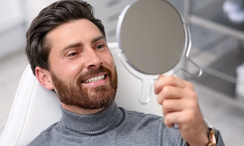 Man admiring his new smile at the dentist’s office