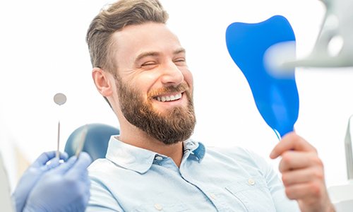 Man admires his smile after dental checkup and cleaning in Braintree