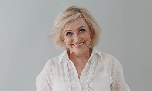 Senior woman in white shirt smiling with dentures