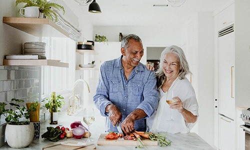 Senior couple smiling while cooking together in kitchen