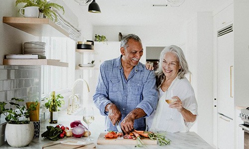 Senior couple smiling while cooking together in kitchen