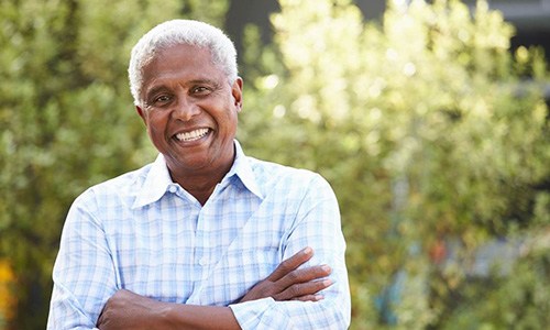 Senior man in blue and white shirt smiling outside