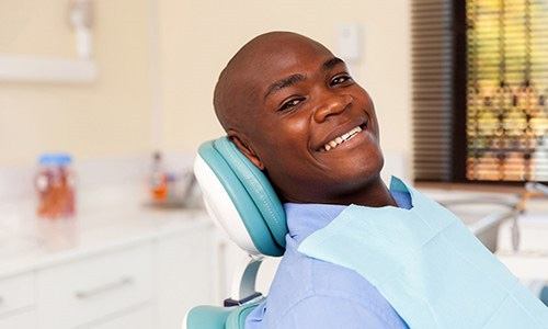 a man smiling while visiting his dentist