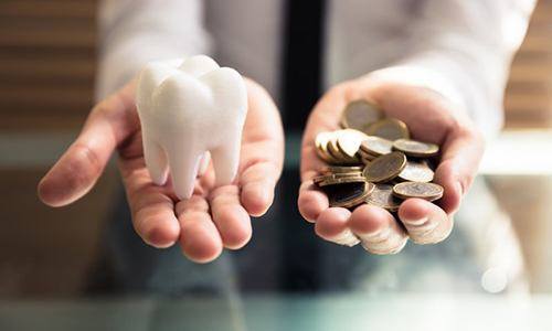 hands holding coins and a model tooth