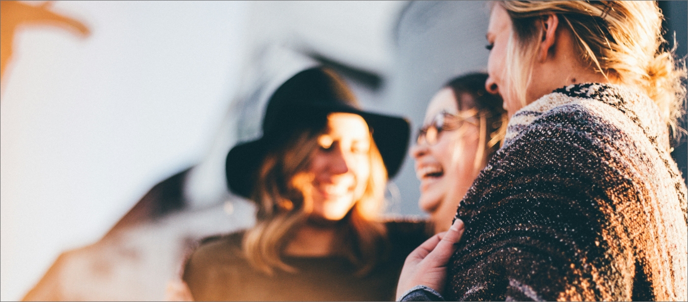 Three people are laughing and talking together outdoors.