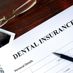 Dental insurance paperwork lying next to glasses and X-ray