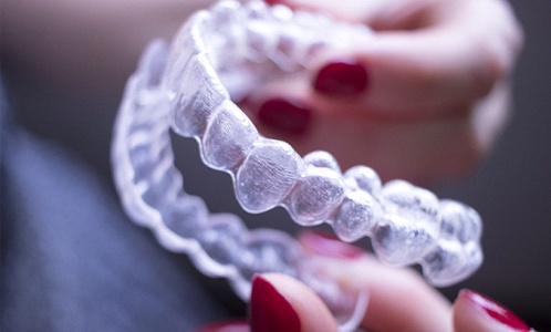 person holding Invisalign aligners