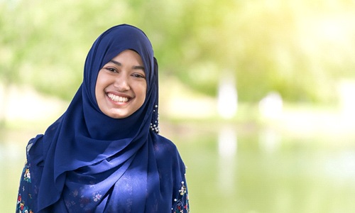 person smiling and standing by a lake