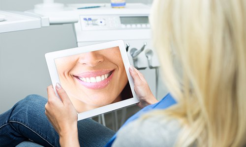 Woman looking at smile design on tablet computer