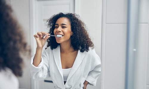Woman brushing her teeth after teeth whitening in Braintree