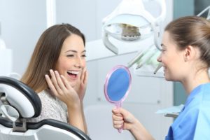 Woman appreciating her smile after visiting her Braintree dentist