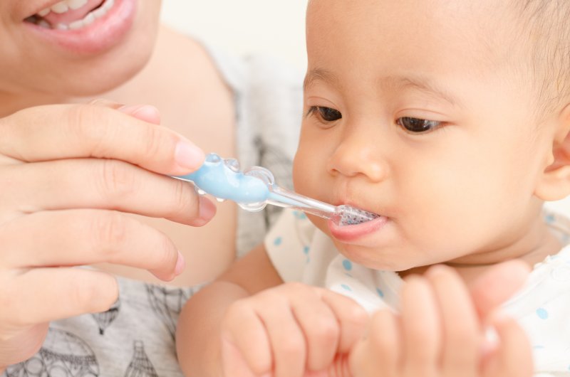 Closeup of mom brushing baby's teeth