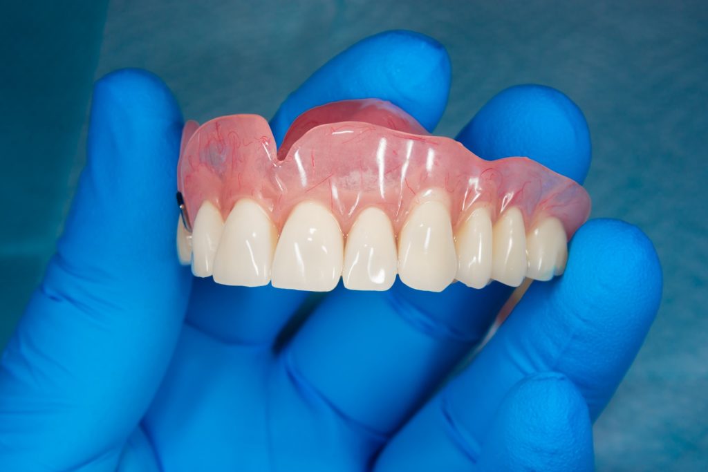 Dentist holding modern dentures