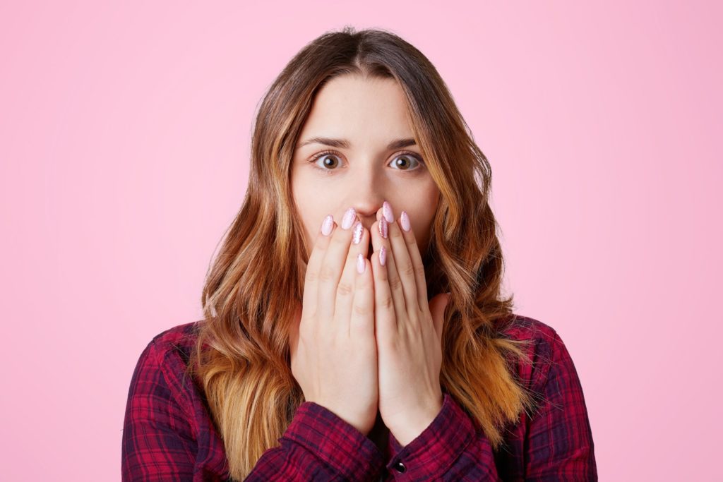 Young woman covering her mouth in shock