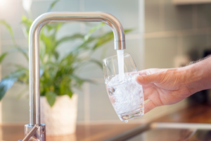 a person filling up a glass with tap water