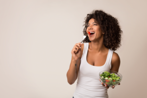 a woman smiling while eating a salad