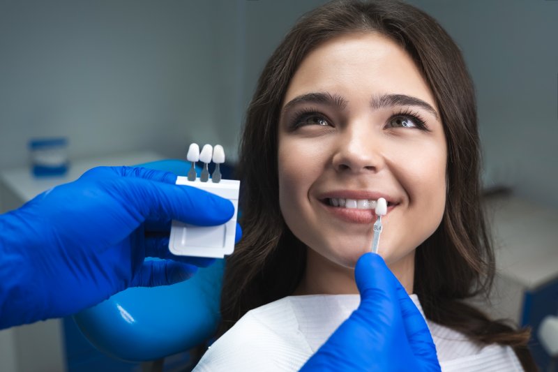 dentist using shade guide on patient’s smile